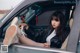 A woman sitting in the driver's seat of a car with her feet up.