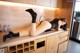 A woman laying on top of a kitchen counter next to a sink.