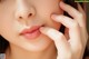 A close up of a woman's face with her hand on her cheek.