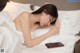 A woman laying in bed with a cell phone in her hand.