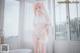 A woman in a white lingerie standing next to a bathtub.