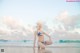 A woman in a bikini sitting on the beach.