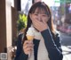 A woman holding an ice cream cone in front of her face.