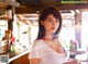 A woman in a white shirt standing in front of a bar.