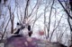 A woman sitting on top of a rock in the woods.