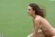 A naked woman sitting on a tennis court.