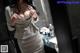 A woman in a beige dress standing in front of a mirror.