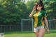 A woman in a green and yellow shirt is standing on a soccer field.